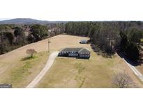 Expansive property featuring a charming brick home, long driveway, outbuilding, and large grassy area surrounded by mature trees at 5715 Due West Nw Rd, Kennesaw, GA 30152