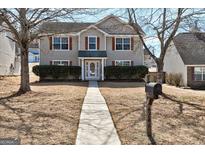 Charming two-story home featuring neutral siding, red shutters, and mature trees at 6746 Lake Erie Ln, Fairburn, GA 30213