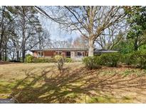 Charming brick home with a spacious front yard and covered porch, surrounded by mature trees and established landscaping at 3600 Old Stilesboro Nw Rd, Kennesaw, GA 30152