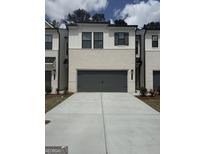 New townhome featuring a gray two-car garage, painted brick, modern black trim and shutters, and concrete driveway at 984 Sutherland Ln # 31, Lawrenceville, GA 30043