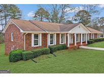 Charming brick home with manicured lawn, white trim windows and inviting columned front porch at 210 Heritage Cir, Mcdonough, GA 30253