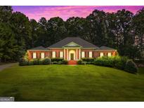 Stately brick home with a manicured lawn and lush landscaping, framed by mature trees at 127 Darwish Dr, Mcdonough, GA 30252