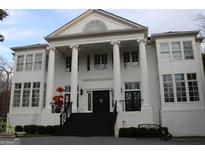Majestic white brick home with grand columns and elegant architectural details for timeless appeal at 337 Lakeshore Dr, Berkeley Lake, GA 30096