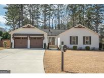 Charming single-story home with two-car garage and well-manicured lawn, beautiful tree line in the background at 100 Lanyard Bnd, Peachtree City, GA 30269