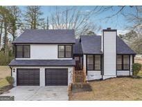 Two-story home featuring a gray roof, two car garage and a well manicured lawn at 1015 Chapman Ln, Stone Mountain, GA 30088