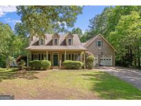 Charming home with a welcoming front porch, well-manicured landscaping, and a two-car garage with basketball hoop at 9209 W Banks Mill Rd, Winston, GA 30187