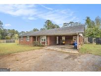 Charming single-story brick home with a covered parking area and a spacious driveway at 1083 Hampton Rd, Hampton, GA 30228