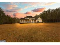 Stately two-story home with a welcoming front porch and a beautifully manicured lawn under a sunset-colored sky at 203 Shelby Ln, Fayetteville, GA 30215