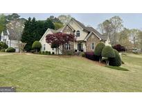 Charming two-story home with stone accents, a well-manicured lawn, and mature landscaping at 1015 Lakeview Knl, Mcdonough, GA 30253
