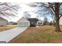 Charming ranch home with a two-car garage, stone accents, and well-maintained lawn at 1632 Zacharys Way, Mcdonough, GA 30253