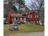 Charming home featuring a brick and wood facade, complemented by a cozy front yard and an outdoor picnic area at 8794 Homewood Dr, Riverdale, GA 30274