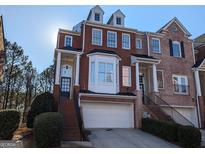 Charming brick townhouse with a two-car garage, complemented by landscaped greenery and inviting entrance stairs at 1272 Creekside Se Ter, Smyrna, GA 30082