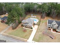 A beautiful two-story home features a backyard oasis with an in-ground pool, lush lawn, and mature trees at 182 Nobility Ln, Mcdonough, GA 30252