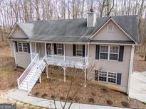 Charming two-story home with light beige siding, a gray roof, and a welcoming front porch at 141 Muirwood Dr, Temple, GA 30179