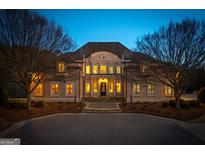 Elegant two-story home featuring a grand entrance, manicured landscaping, and a circular driveway at twilight at 300 Annelise Park Dr, Fayetteville, GA 30214