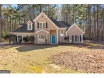 Charming two-story traditional home with a well-manicured lawn, complemented by mature trees and a bright blue front door at 135 Weeping Willow Way, Tyrone, GA 30290