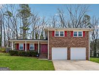 Charming brick home with a two car garage, red shutters, green lawn and mature trees at 3216 Pheasant Dr, Decatur, GA 30034