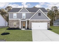 New two-story home showcasing a well manicured lawn and a gray and brick facade at 3121 Azteca Way, Dacula, GA 30019