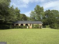 Unique brick home featuring arched entryways, a black roof, and a lush lawn at 5142 Rock Eagle Dr, Stone Mountain, GA 30083