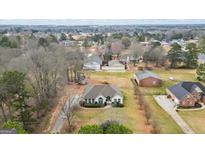 Sprawling home featuring lush lawns, mature trees and manicured landscaping in a serene residential neighborhood at 3403 Bill Gardner Pkwy, Locust Grove, GA 30248