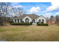 Charming white brick home with a well-manicured lawn and a bright blue front door at 3403 Bill Gardner Pkwy, Locust Grove, GA 30248