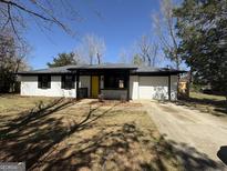 Charming ranch-style house with a bright yellow front door and an attached one-car garage at 95 Grove Creek Dr, Locust Grove, GA 30248