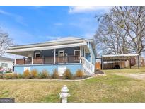 Charming blue home featuring a metal roof, inviting front porch and a convenient carport at 1616 Park Ne St, Conyers, GA 30012