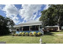 Charming blue home featuring a quaint front porch, a metal roof, and a well-maintained lawn at 1616 Park Ne St, Conyers, GA 30012