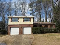 Split-level home with a two-car garage, brick accents, and a well-maintained front yard, under a sunny sky at 3892 Northstrand Dr, Decatur, GA 30035