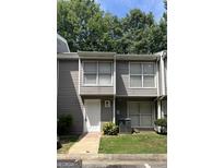 Exterior view of the townhome with gray siding, white door and trim and green landscaping in front at 186 Governors Dr, Forest Park, GA 30297