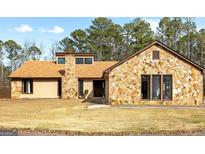 Charming stone-accented home with a well-maintained lawn and natural light in a tranquil wooded setting at 150 Old Mill Pt, Fayetteville, GA 30214