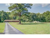 Well-maintained brick home with a spacious front yard and mature trees at 677 Gum Creek Rd, Oxford, GA 30054