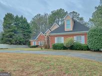 Charming brick home with dormer window, shutters, mature trees, and ample driveway space at 603 Champions Dr, Mcdonough, GA 30253