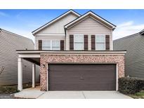 Charming two-story home features a brick facade, two-car garage and a welcoming covered entryway at 323 Lauren Dr, Fairburn, GA 30213