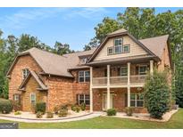 Stunning brick home featuring a charming two-story porch and beautifully landscaped front yard at 105 Dockstreet Aly, Peachtree City, GA 30269