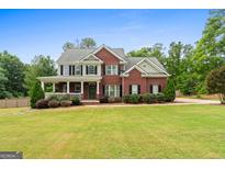 Charming two-story brick home with a inviting front porch and meticulously manicured lawn at 100 Coldwater Creek Dr, Mcdonough, GA 30252