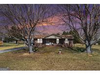 Charming brick ranch home featuring a well-manicured lawn, mature trees, and a cozy front porch with rocking chairs at 143 Teamon Rd, Hampton, GA 30228