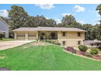 Charming ranch home featuring a two-car garage, covered porch, and mature trees at 3231 Boulder Brook Dr, Lithonia, GA 30038
