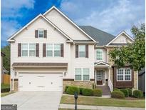 Charming two-story home with a two-car garage, stone accents, and manicured landscaping at 1318 Avington Glen Dr, Lawrenceville, GA 30045