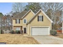 Two-story home with a two-car garage, tan stucco, and attractive stone facade accents at 12241 Crestwood Ct, Fayetteville, GA 30215