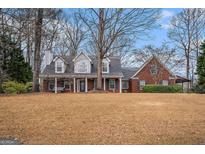 Charming brick home with a covered front porch and mature trees on a large lawn at 149 Crown Oaks Dr, Stockbridge, GA 30281