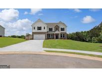 Two-story home with a brick and white shingle exterior, two-car garage, and lush green lawn at 127 Felicity Pike, Locust Grove, GA 30248