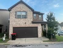 Two-story brick home featuring an attached two-car garage and manicured landscaping at 6001 Nile Ct, Atlanta, GA 30349