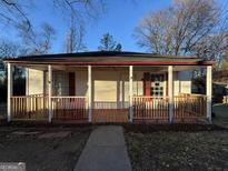 Charming home featuring a cozy front porch and freshly painted red and white trim, offering a warm and inviting curb appeal at 18 Laurel St, Covington, GA 30014