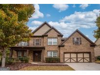 Beautiful two-story brick home with a two-car garage, front porch, and manicured landscaping at 5825 Trailwood Ct, Suwanee, GA 30024
