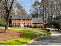 Charming two-story brick home featuring a manicured lawn and mature trees at 1121 Valley Ridge Ct, Marietta, GA 30067