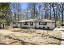 Charming single-story home with a brick exterior, black shutters, and mature trees in a quiet neighborhood at 5595 Richland Dr, Douglasville, GA 30135