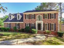 Charming two-story brick home featuring black shutters, a manicured lawn, and a welcoming front entrance at 105 Windridge Dr, Fayetteville, GA 30215