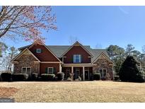 Charming two-story home with a stone and wood facade, complemented by a well-maintained lawn and colorful flowering tree at 108 Caraway Rd, Locust Grove, GA 30248