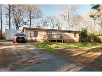Charming single-story home featuring a wooden deck, well-maintained lawn, and a parked red Ford SUV at 105 Woodfield Rd, Covington, GA 30014